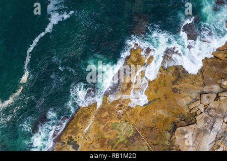 Aerial, overhead view of waves and a rocky shoreline in Sydney, Australia Stock Photo