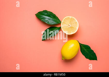 Half and whole lemon on a living coral background. Stock Photo