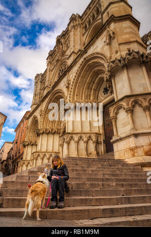 A blonde woman and her blonde border collie mix dog eating a sandwich on the steps of a gothic building in Spain with a blue sky and white clouds abov Stock Photo