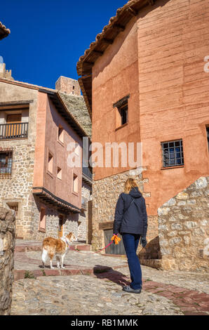 Blonde woman walking with her blonde border collie mix dog on the small ancient winding streets of Albarracin Spain on a bright crisp fall day with a  Stock Photo