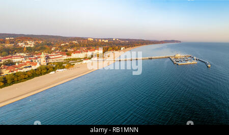 Wide aerial panorama of Sopot resort near Gdank in Poland in sunrise light. Wooden pier (molo) with marina, yachts, beach, old lighthouse, vacation in Stock Photo