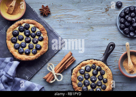 Delicious Blueberry tartlets with vanilla custard cream on light rustic wooden background. Top view with copy-space Stock Photo