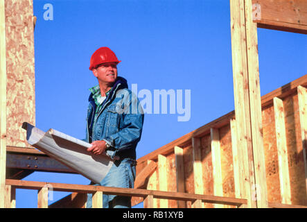 Man with Plans oversees Home Construction in a suburban neighborhood, United States Stock Photo