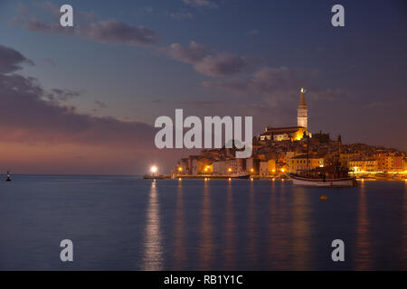 View of the city of Rovinj in Croatia. Blue light sunset with city lights turning on. Blurry boats movement from Long Exposure Stock Photo