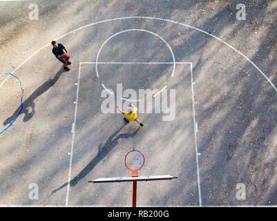 Father and son playing basketball in the park aerial view