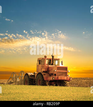 Tractor cultivating the field on sunrise Stock Photo