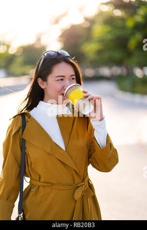 Cheerful girl with cup of coffee walking outdoors Stock Photo