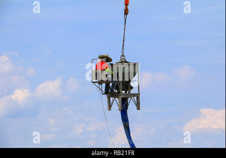 crane lifting concrete mixer container and worker in construction building commercial  in site workplace Stock Photo