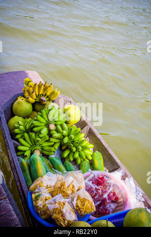 fruit and bunches of bananas on a wooden canoe sold from the river bank in Thailand Stock Photo