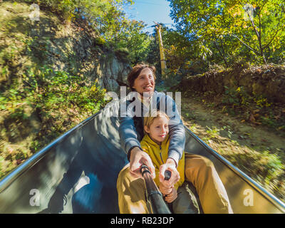 Dad and son have fun on alpine roller coaster Stock Photo