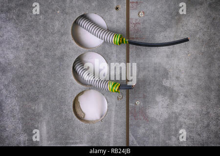 Plastic corrugated pipes with electric cable inside sticking out of wall for power sockets. Close-up. Stock Photo