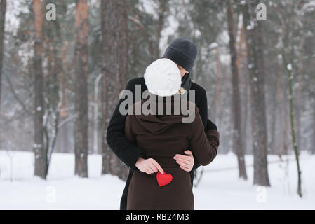 Romance Valentines Day. Happy couple kissing. Man holding a red decorative heart Stock Photo