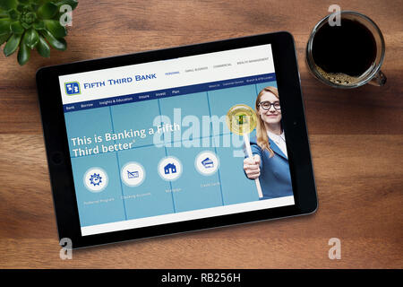 The website of Fifth Third Bank is seen on an iPad tablet, on a wooden table along with an espresso coffee and a house plant (Editorial use only). Stock Photo