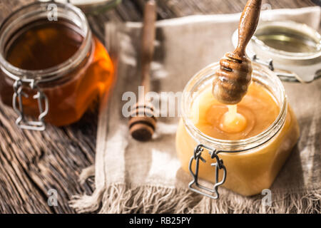 Honey in jars and  dipper on rustic oak table. Stock Photo