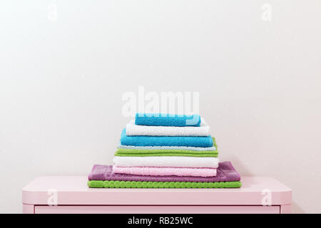 On the chest lies a stack of stacked colorful towels. Stock Photo