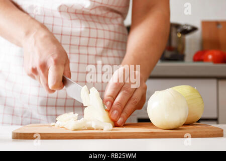 Woman cooking at home in the kitchen, cutting onions on a wooden board. Healthy fresh food. Close-up Stock Photo