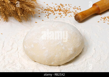 Raw fresh dough in the flour and ears of wheat on a white background Stock Photo
