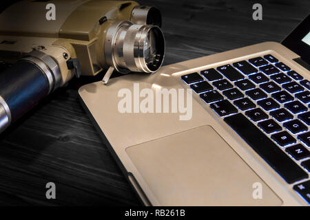 Contrast between different periods of technology: a vintage Super 8 cine camera from the 1960 Minolta Zoom 8 with an actual computer laptop Apple Macb Stock Photo