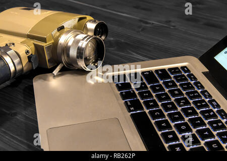 Contrast between different periods of technology: a vintage Super 8 cine camera from the 1960 Minolta Zoom 8 with an actual computer laptop Apple Macb Stock Photo
