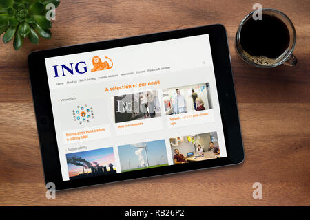 The website of ING Bank is seen on an iPad tablet, on a wooden table along with an espresso coffee and a house plant (Editorial use only). Stock Photo