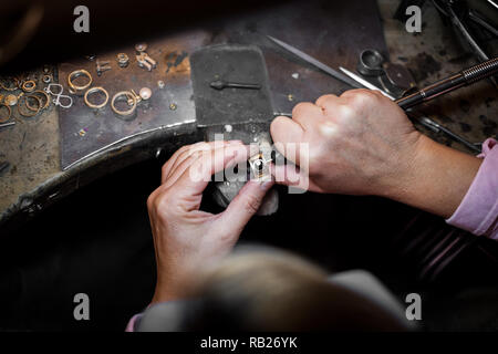 Jeweler polishes a gold ring on an old workbench in an authentic jewelry workshop Stock Photo