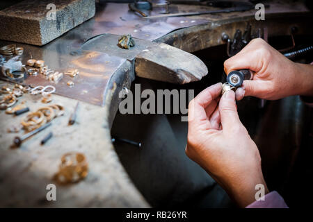 Jeweler polishes a gold ring on an old workbench in an authentic jewelry workshop Stock Photo