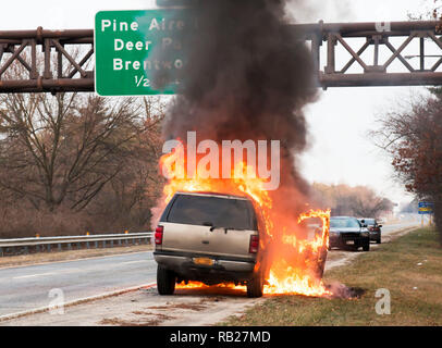A brown car on fire on the side of the highway on long island, NY Stock Photo