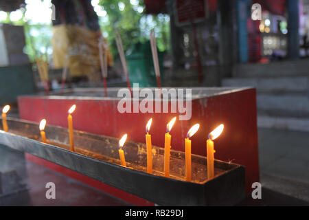 Buddhists make merit,Placing a lighted candle and lit incense with candles frame on the altar of Buddha  at temple.  Selective focus. Stock Photo