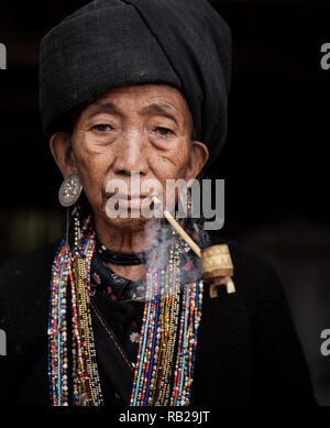 KYAING TONG, MYANMAR - CIRCA DECEMBER 2017: Portrait of elder woman of the Wan Sai Akha Village in Kyaing Tong smoking. Stock Photo