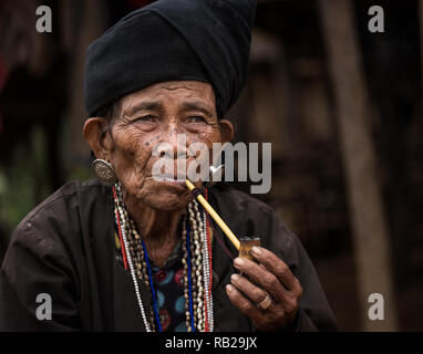 KYAING TONG, MYANMAR - CIRCA DECEMBER 2017: Portrait of elder woman of the Wan Sai Akha Village in Kyaing Tong smoking. Stock Photo