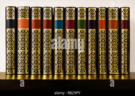 Antique looking books with golden decoration and colorful bands on a shelf Stock Photo