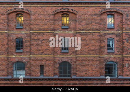 Facade in the historic warehouse district in Hamburg with a lit window Stock Photo