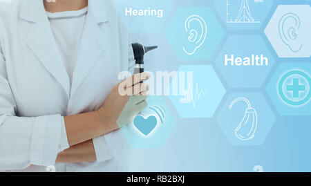 Doctor holding otoscope with hearing icons flow on virtual screen.concept illustrates future technologies for the treatment of hearing Stock Photo