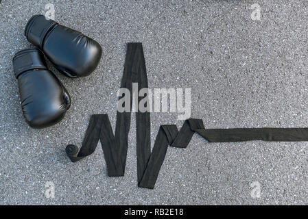 High pulse rate. Close-up of sports boxing gloves with boxing bandages at the asphalt background Stock Photo