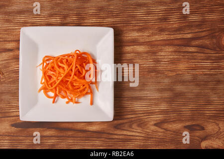 Grated carrots in a white cup isolated on a wooden background. Isolate. Stock Photo