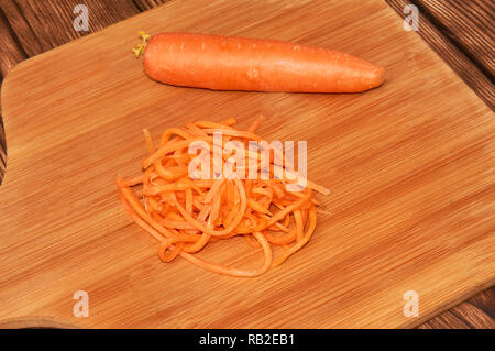 Grated and whole carrots, on a wooden background. Stock Photo