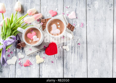 Valentines day treat ideas, two cups hot chocolate drink with marshmallow hearts red pink white color with chocolate pieces, sugar sprinkles, old wood Stock Photo