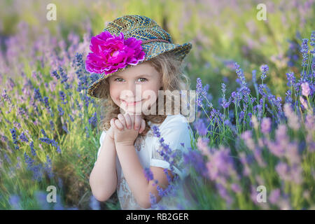 Young beautiful girl walking on the lavender field on a weekend day in wonderful dresses and hats Stock Photo