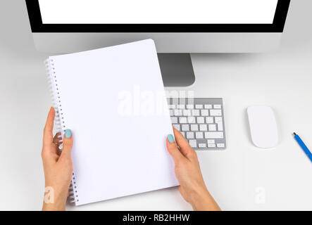 Business woman hands holding notebook with space for text. Business workplace with computer with isolated empty screen and wireless mouse and keyboard Stock Photo