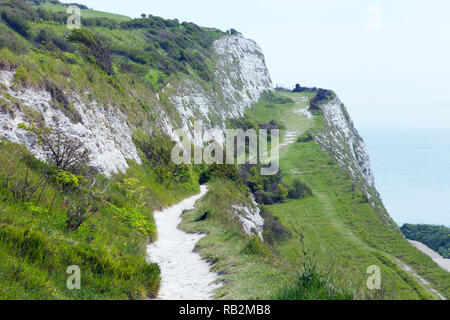 Coastal walking path on top of white chalk cliffs, overlooking the English Channel, Dover, Kent, south east England, on a hazy summer day . Stock Photo