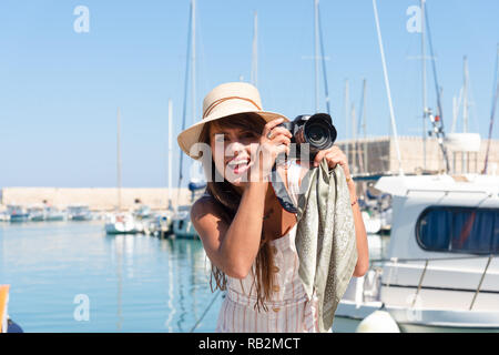 Traveling tourist woman on vacation in Heraklion Crete visiting the port. Lovely elegant girl takes pictures at the famous Mediterranean Venetian port Stock Photo