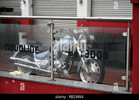 Cologne, Germany. 6th Jan 2019.  Bullet holes can be seen in a glass pane in front of an amusement arcade in the Buchheim district - a motorcycle stands in front of the building. Unknown persons had fired more than a dozen shots from a weapon on 04.01.2019. Photo: Henning Kaiser/dpa Credit: dpa picture alliance/Alamy Live News Credit: dpa picture alliance/Alamy Live News Stock Photo