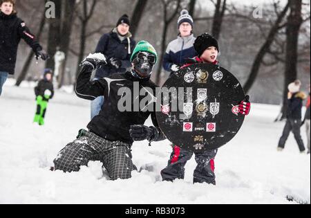 Munich, Bavaria, Germany. 6th Jan, 2019. A masked participant of the Munich snowball fight teams up with a child holding a shield to attack the other teams. Hundreds of winter revelers in Munich, Germany hold a snowball fight in the famed English Garden. Over the past week, southern Germany and Austria experienced periods of heavy, sometimes prolonged snowfall with significant accumulations leading to difficult driving conditions and mass transit delays. Credit: Sachelle Babbar/ZUMA Wire/Alamy Live News Stock Photo