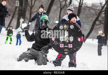Munich, Bavaria, Germany. 6th Jan, 2019. A masked participant of the Munich snowball fight teams up with a child holding a shield to attack the other teams. Hundreds of winter revelers in Munich, Germany hold a snowball fight in the famed English Garden. Over the past week, southern Germany and Austria experienced periods of heavy, sometimes prolonged snowfall with significant accumulations leading to difficult driving conditions and mass transit delays. Credit: Sachelle Babbar/ZUMA Wire/Alamy Live News Stock Photo