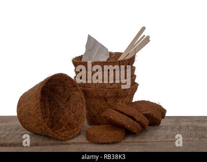 Coir plant pots and compressed compost with seeds and wooden labels. Environmentally friendly spring gardening. Isolated on white background. Stock Photo