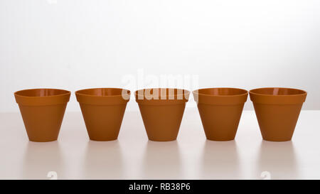 Row of plastic flower pots on white background with reflection. Stock Photo
