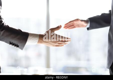 close up. handshake business people standing near the window in the office Stock Photo