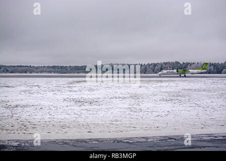 ARLANDA, SWEDEN - DECEMBER 31, 2018: Small aircraft from Air Baltic on runway in snow and ice on airport tarmac on an overcast day on December 31, 201 Stock Photo
