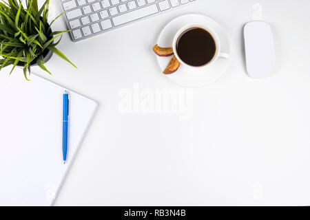 Office desk with copy space. Digital devices wireless keyboard and mouse on office table with notepad and cup of coffee, top view Stock Photo