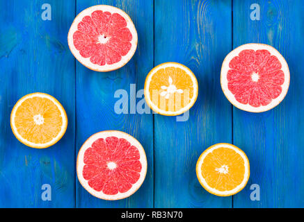 Fresh half cut grapefruit and orange on a blue wooden background, close up view Stock Photo